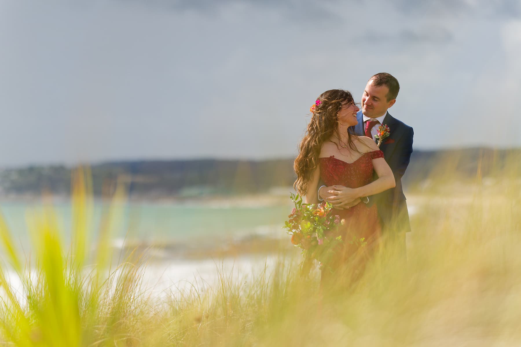 Bride and groom among coastal grasses on the Cornwall coast near Penzance