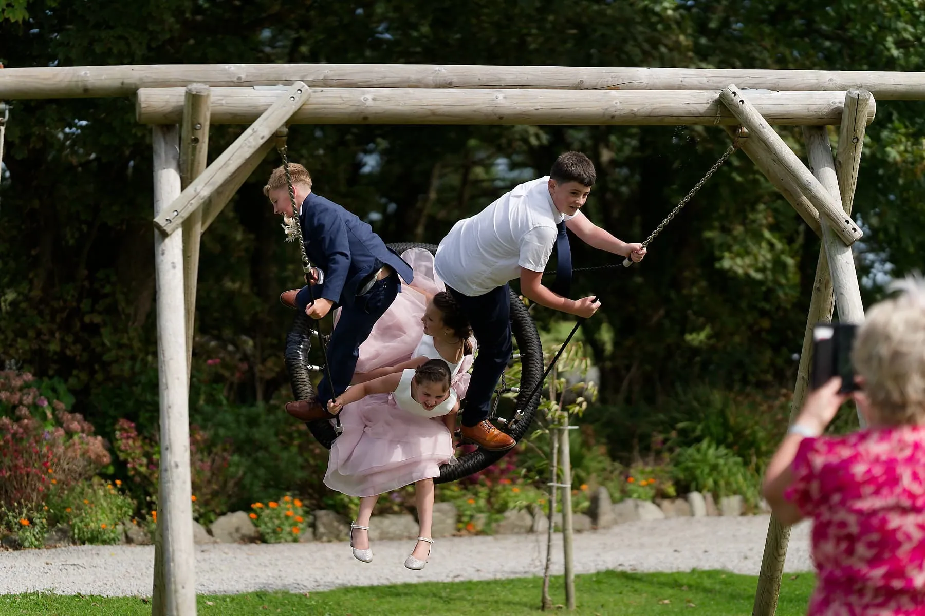 Children from a Cornwall wedding party playing together on a garden swing