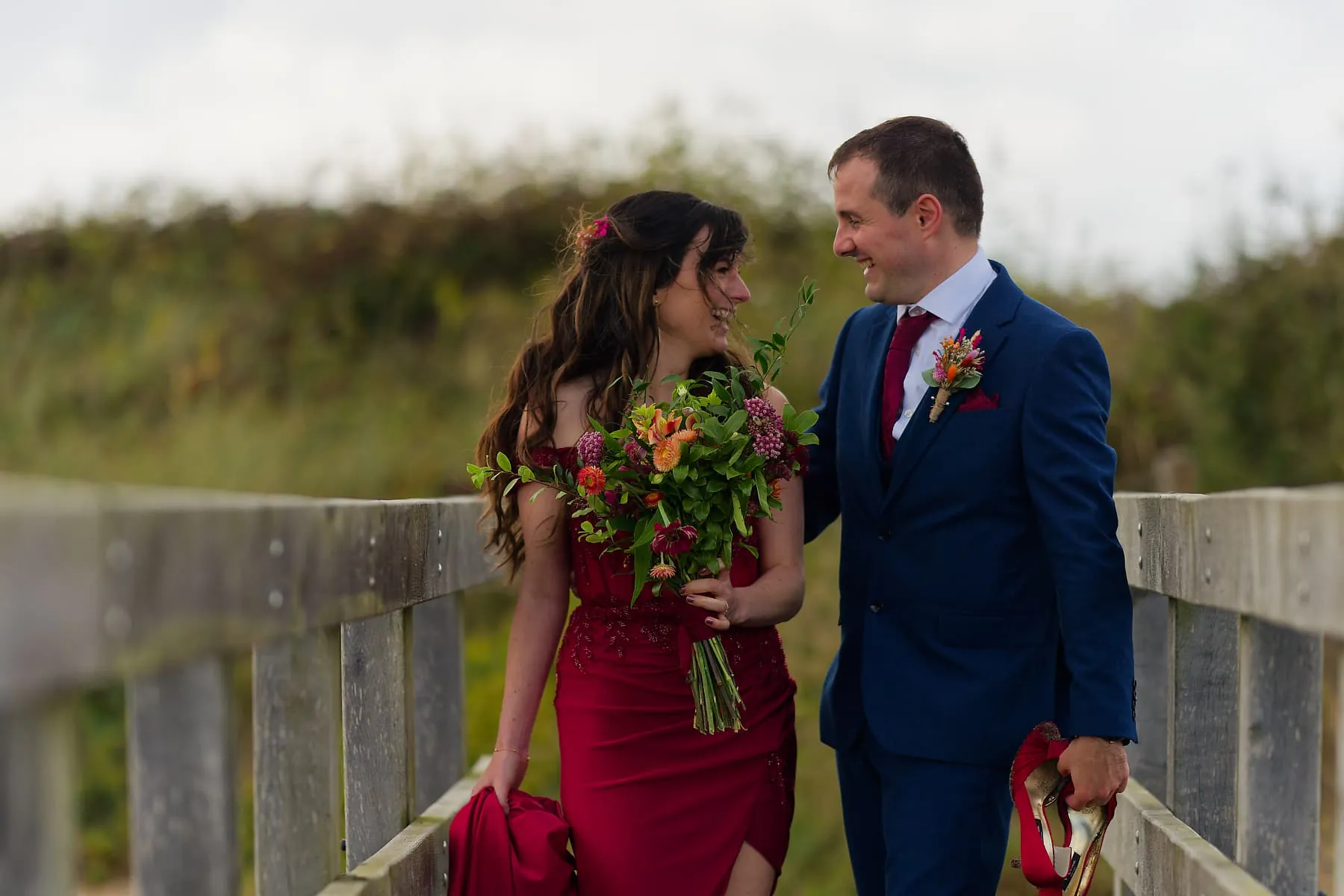 Newlyweds walking a coastal boardwalk during their west Cornwall wedding