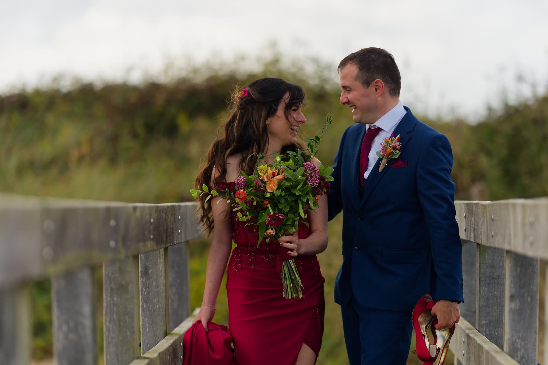 Newlyweds walking a coastal boardwalk during their west Cornwall wedding