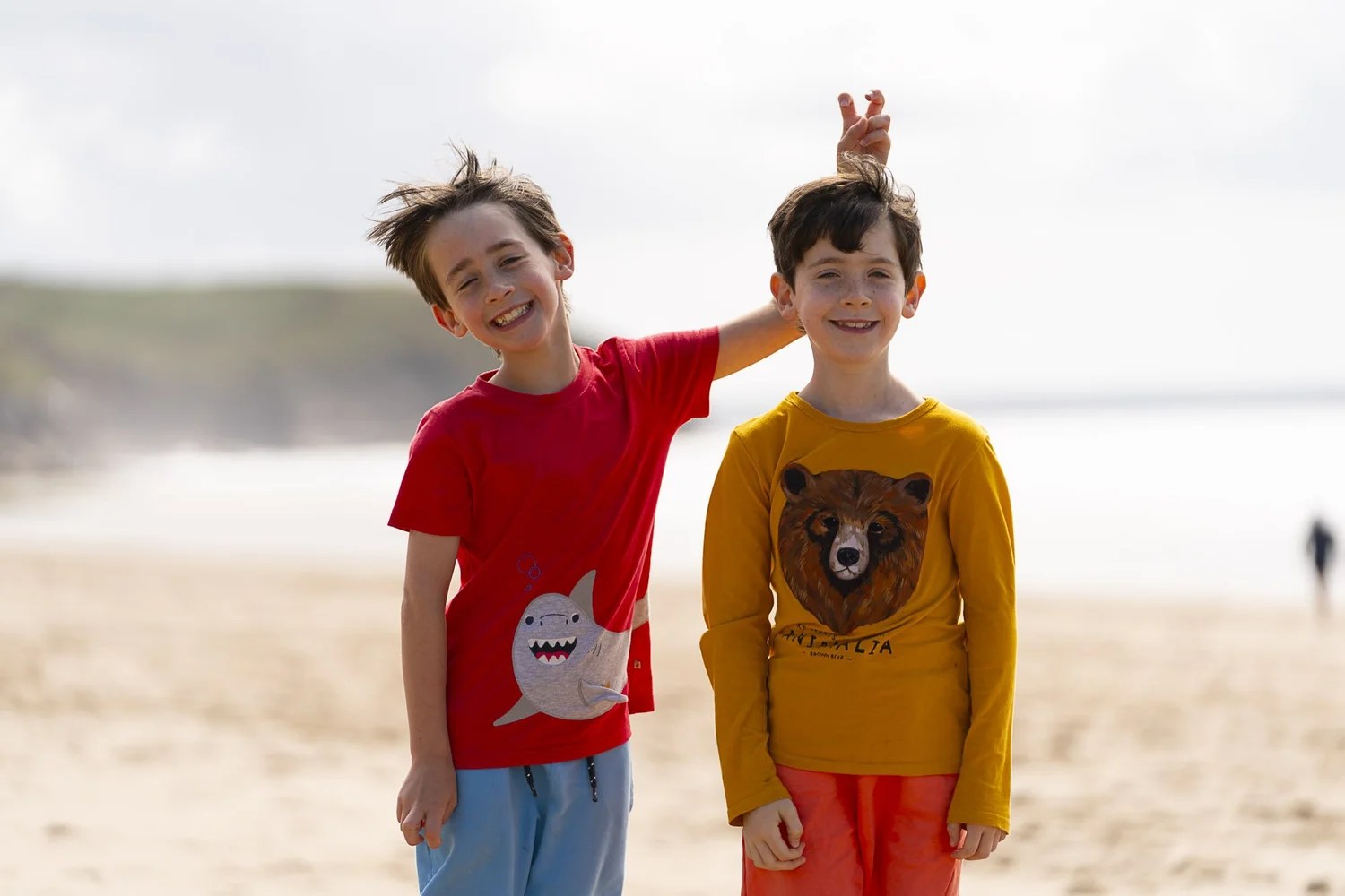 Two brothers standing together on a wide Cornish beach during a family photography session near Penzance