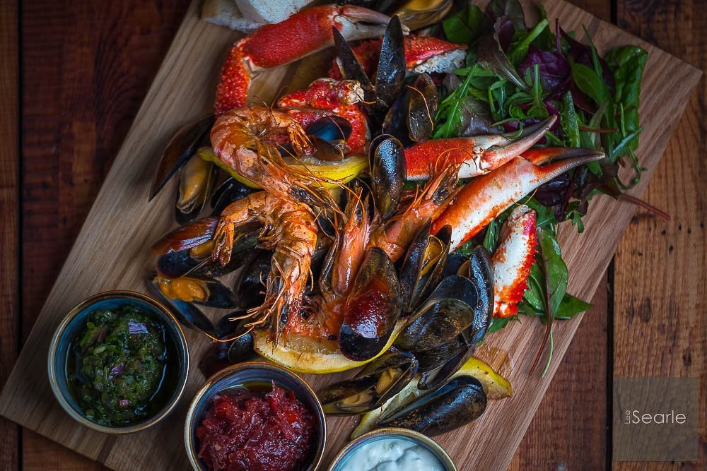Cornish seafood platter with prawns, mussels and crab on a wooden board