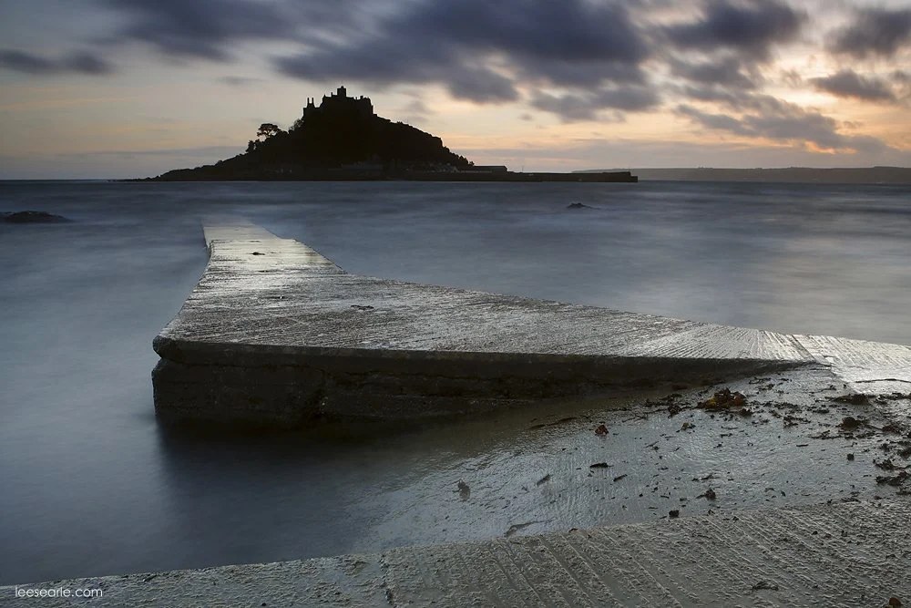 St Michael's Mount at dusk seen across the slipway and wet sand at Marazion, Cornwall