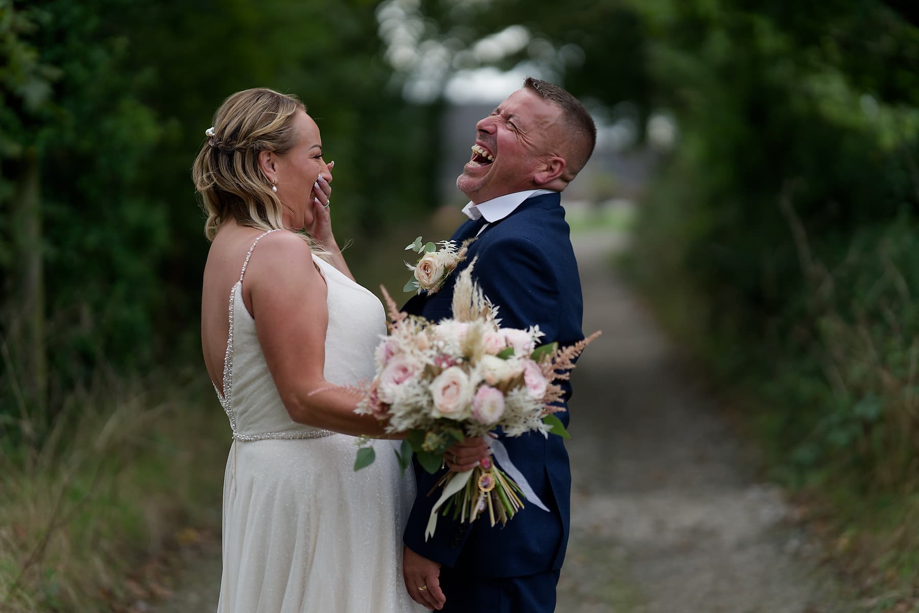 Bride and groom laughing together on a country lane after their Cornwall wedding