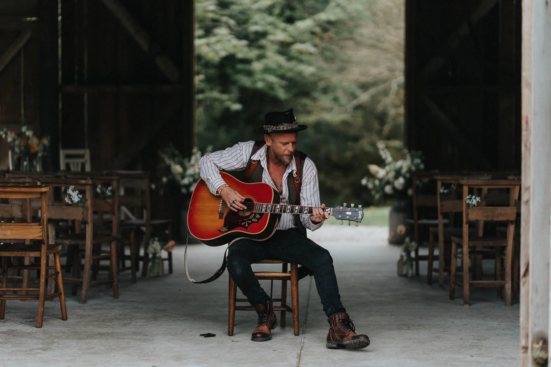Lee Searle playing guitar inside a rustic barn before a Cornwall wedding