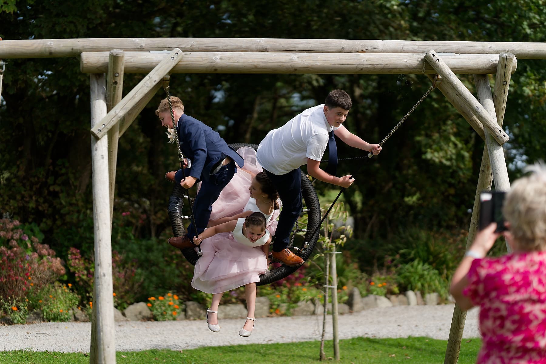Children from a Cornwall wedding party playing together on a garden swing