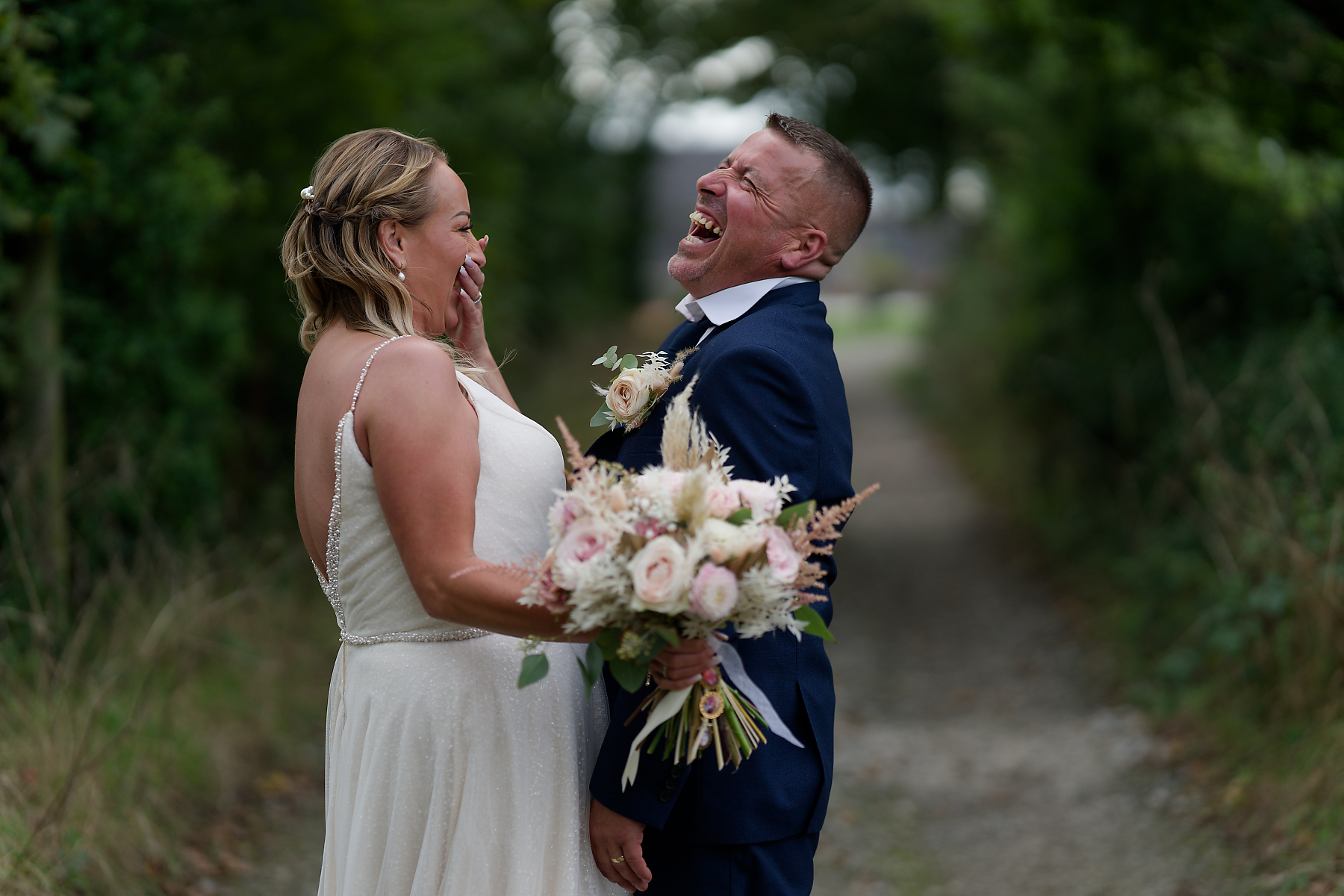 Bride and groom laughing helplessly on a country lane