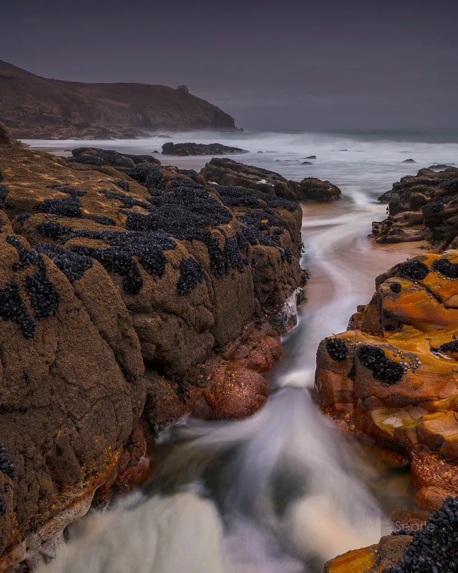 Long exposure of a stream tumbling over rocks into the sea on the Cornish coast