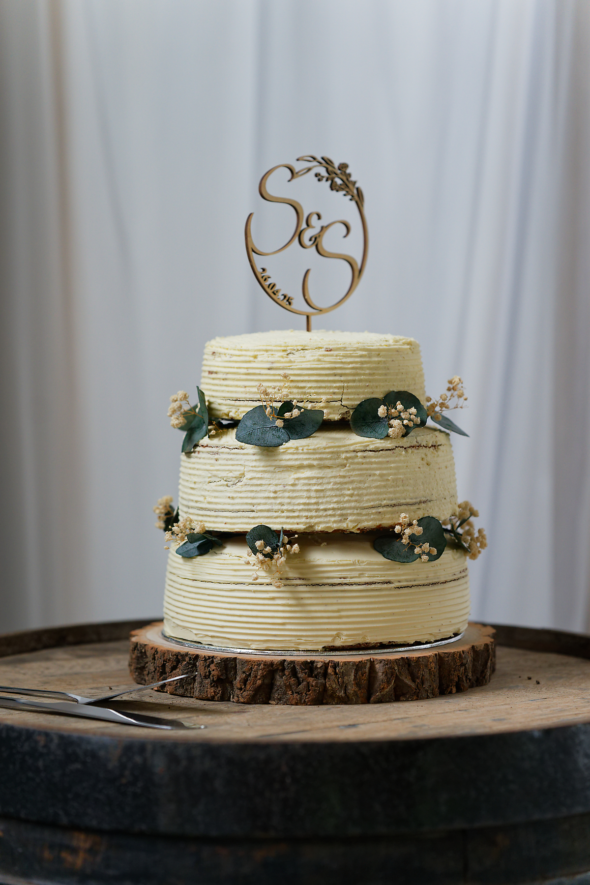 Three-tier wedding cake topped with a wooden monogram