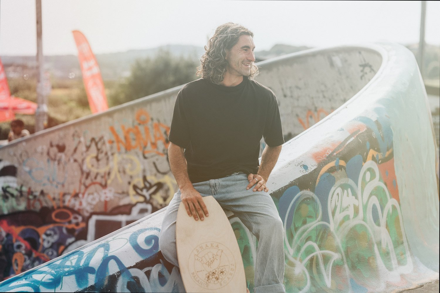 Portrait of a skater leaning on his board against graffiti, lifestyle brand photography in Cornwall
